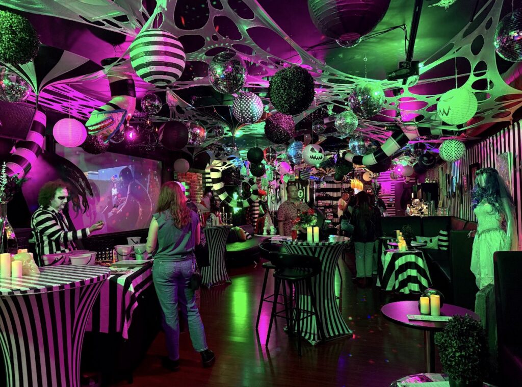 Beetlejuice character at a spooky Halloween bar in Pittsburgh decorated with cobwebs and disco balls.
