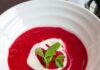 Jessica Lewis’s Polish Borscht A bowl of vibrant red Polish Borscht beet soup, garnished with a swirl of crème fraîche and fresh pea shoots.