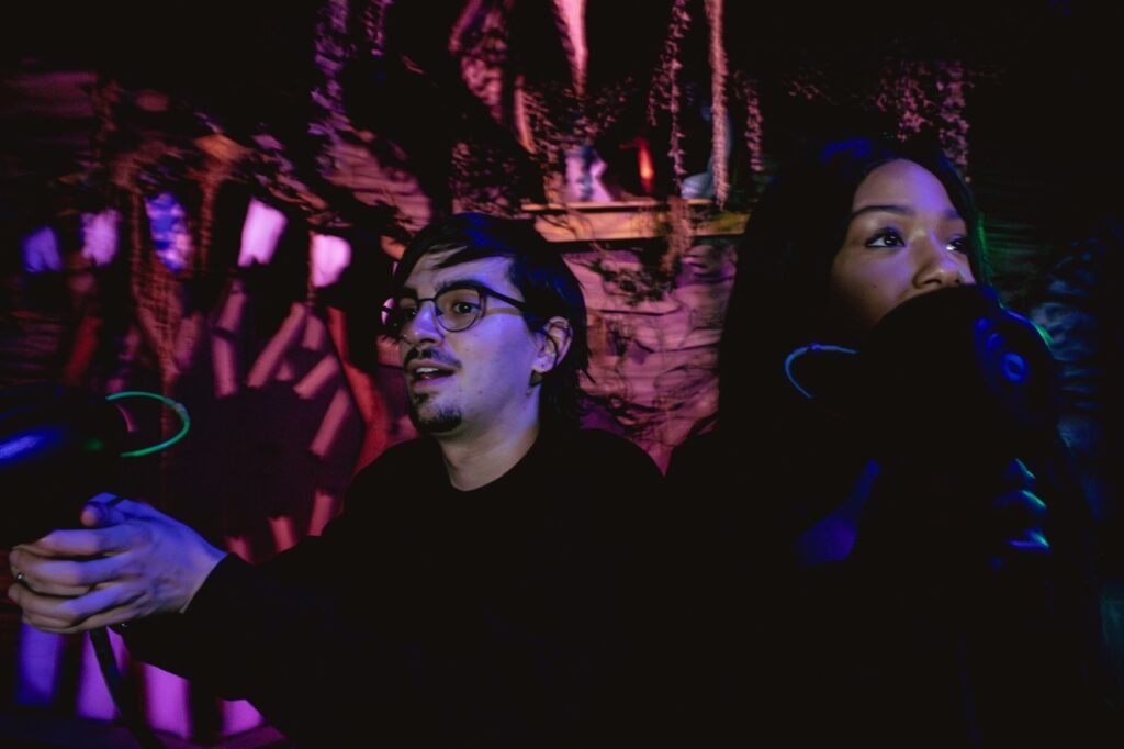 A man and woman shoot ghosts in a ride.