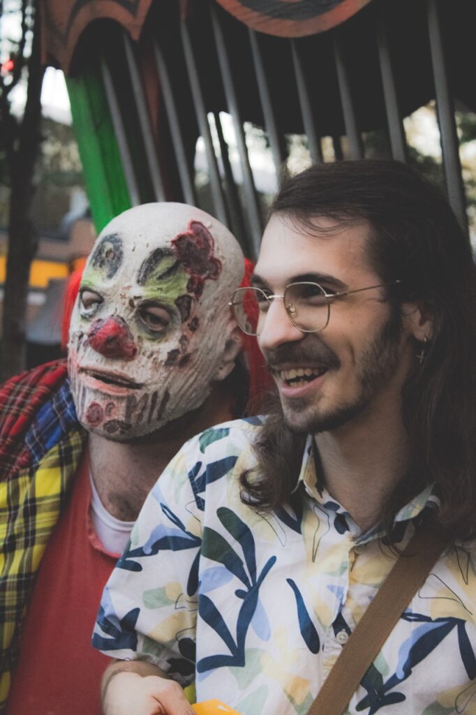 A person in a clown mask beside a smiling man.