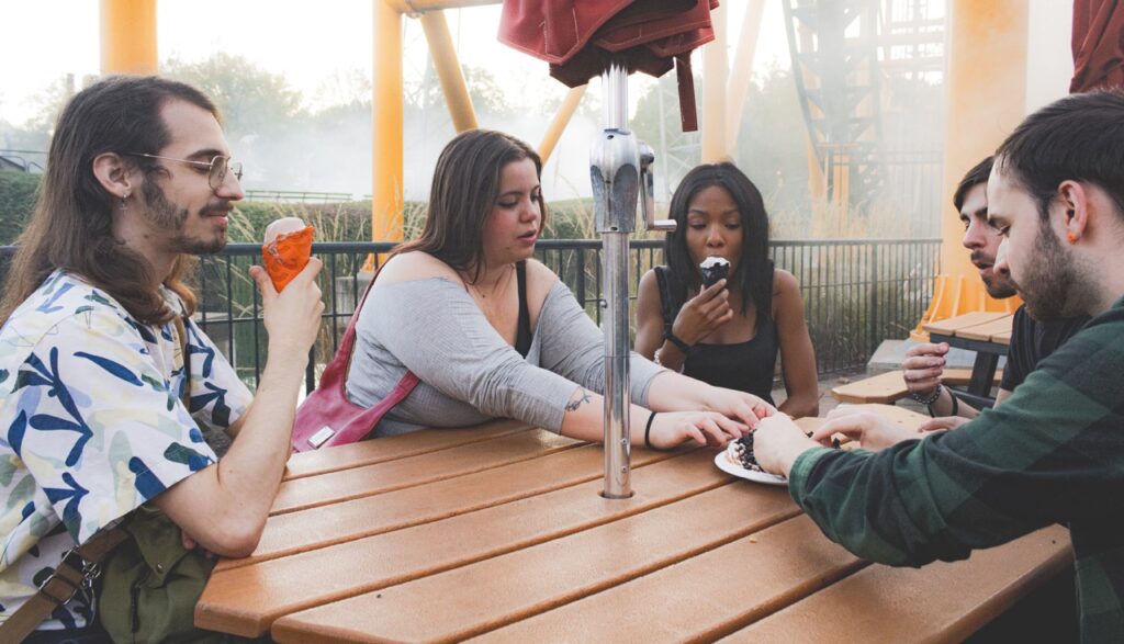 A group of people share ice cream cones and funnel cake.