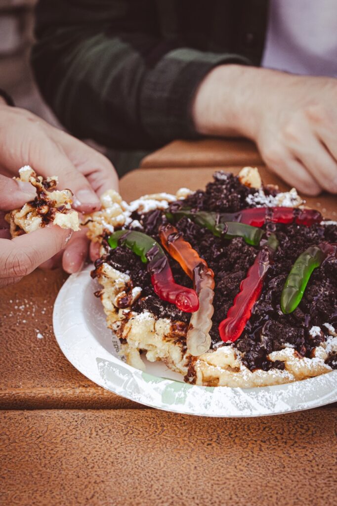 A person pulls off a piece of funnel cake.