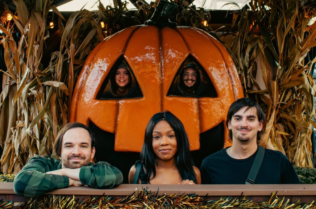 A group of people pose in a pumpkin prop.