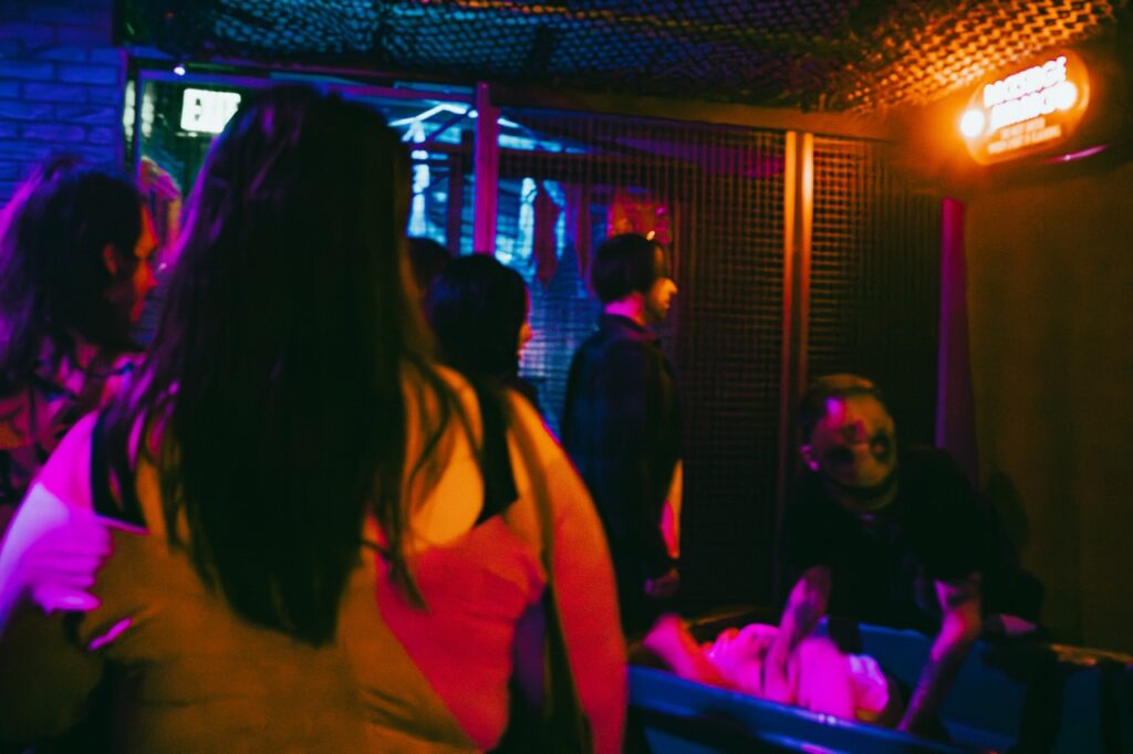 A group of people walk through the alley of a haunted house.