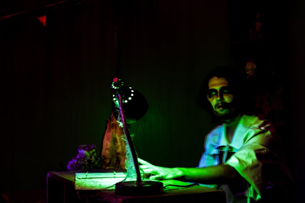 A man in a green eerie lamp light.