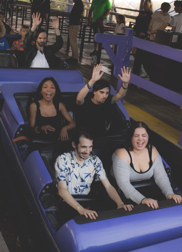Four people in a purple rollercoaster car.