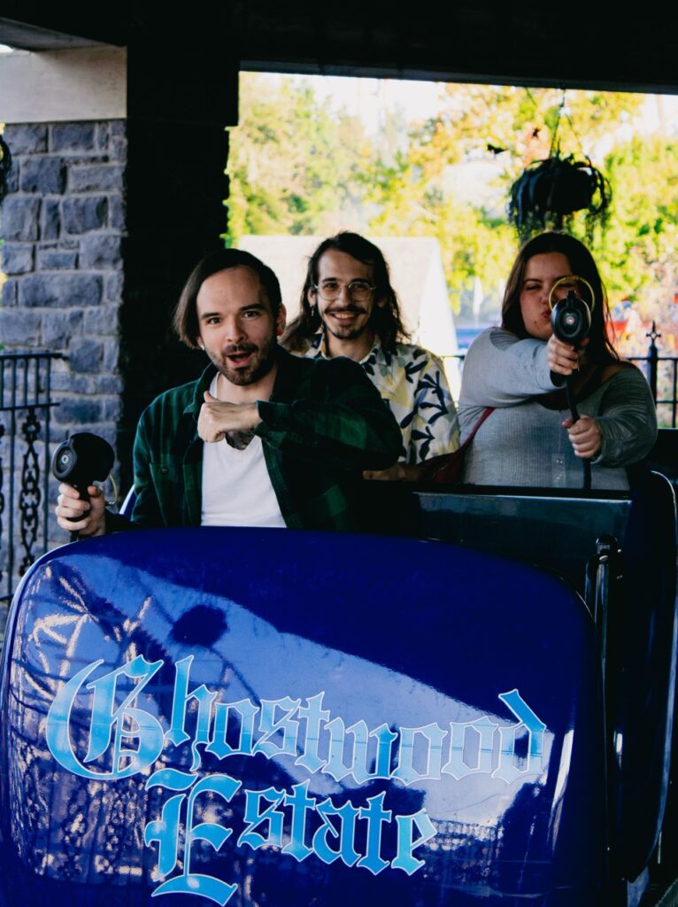 Three people sit in a purple ride cart.