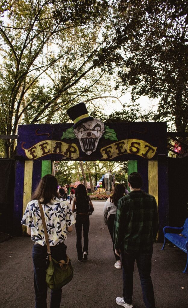 A group of people walking through a Fear Fest clown sign.
