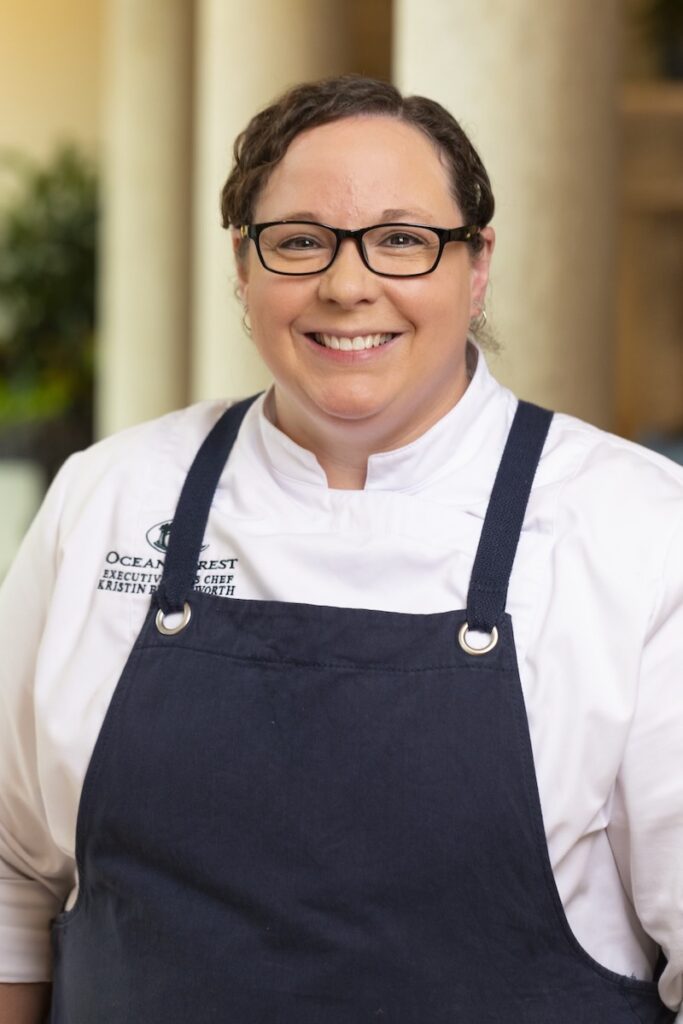 Kristin Butterworth stands in a black apron and white chefs shirt.