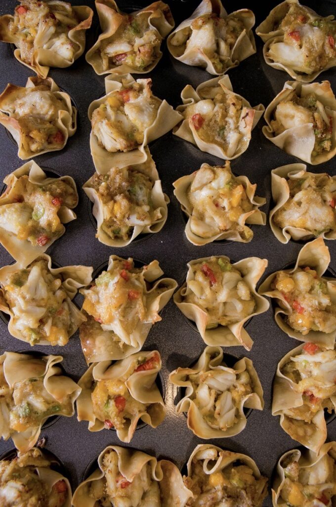 A bunch of small full wontons in muffin sheet type pans.