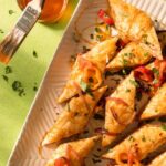 Savory Romesco Baklava triangles drizzled with hot honey and topped with sliced peppers and parsley, ready to serve.