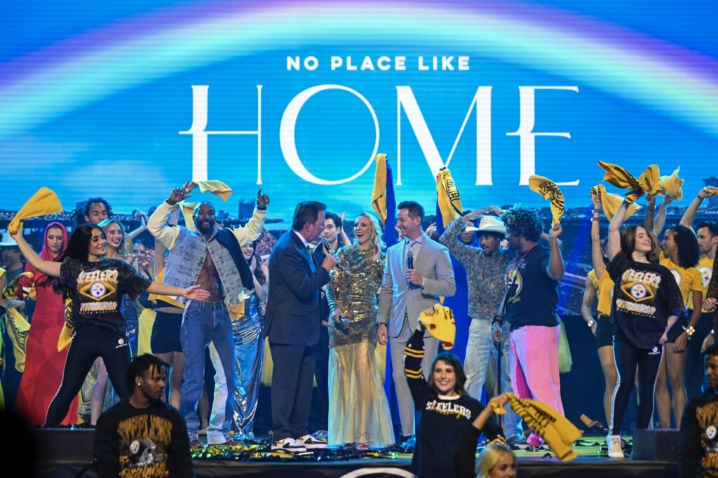 A large group of people on a stage waving yellow towels in the air.