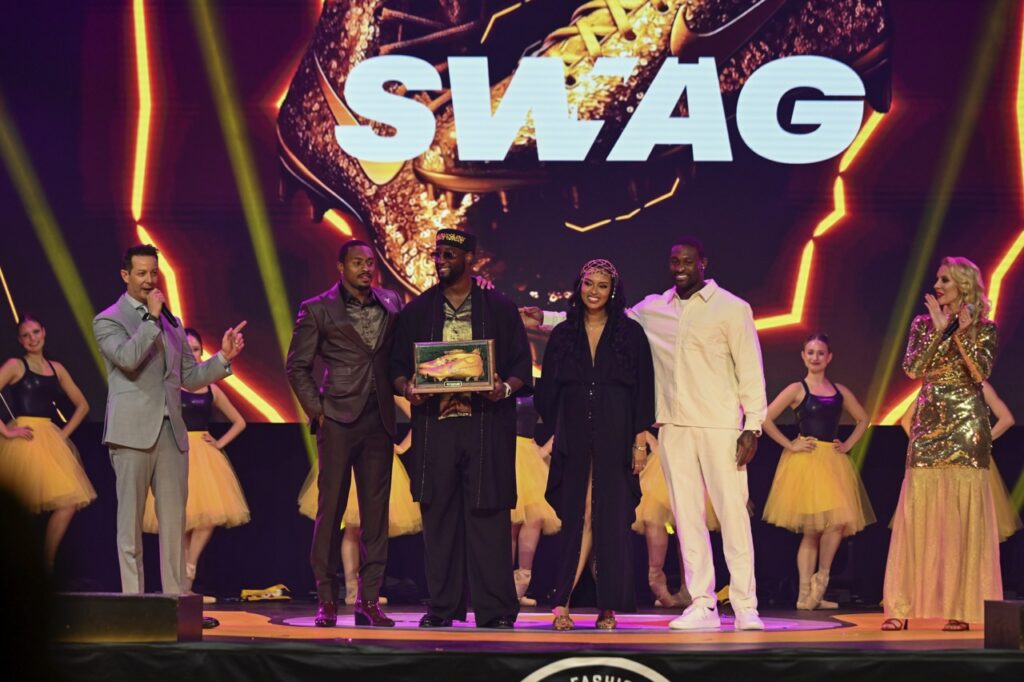 A group of people stand on a stage in black and white to accept an award.