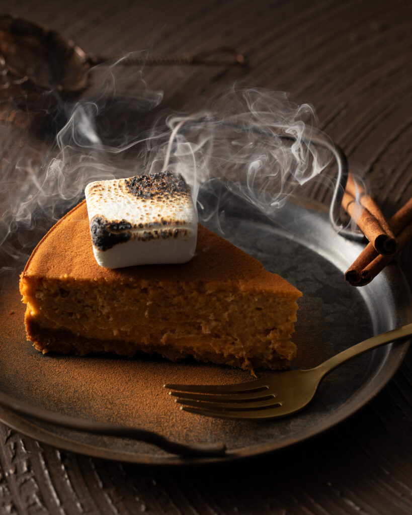A slice of sweet potato cheesecake topped with marshmallows, elegantly presented on a white plate, showcasing its creamy texture.