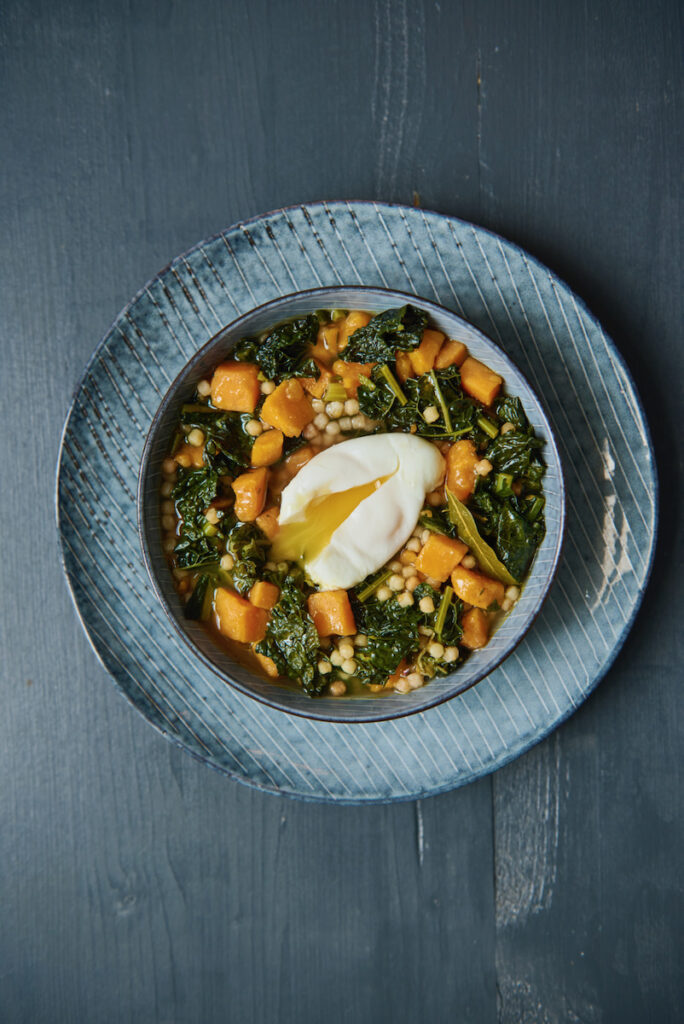 A plate of kale and sweet potato soup with a poached egg