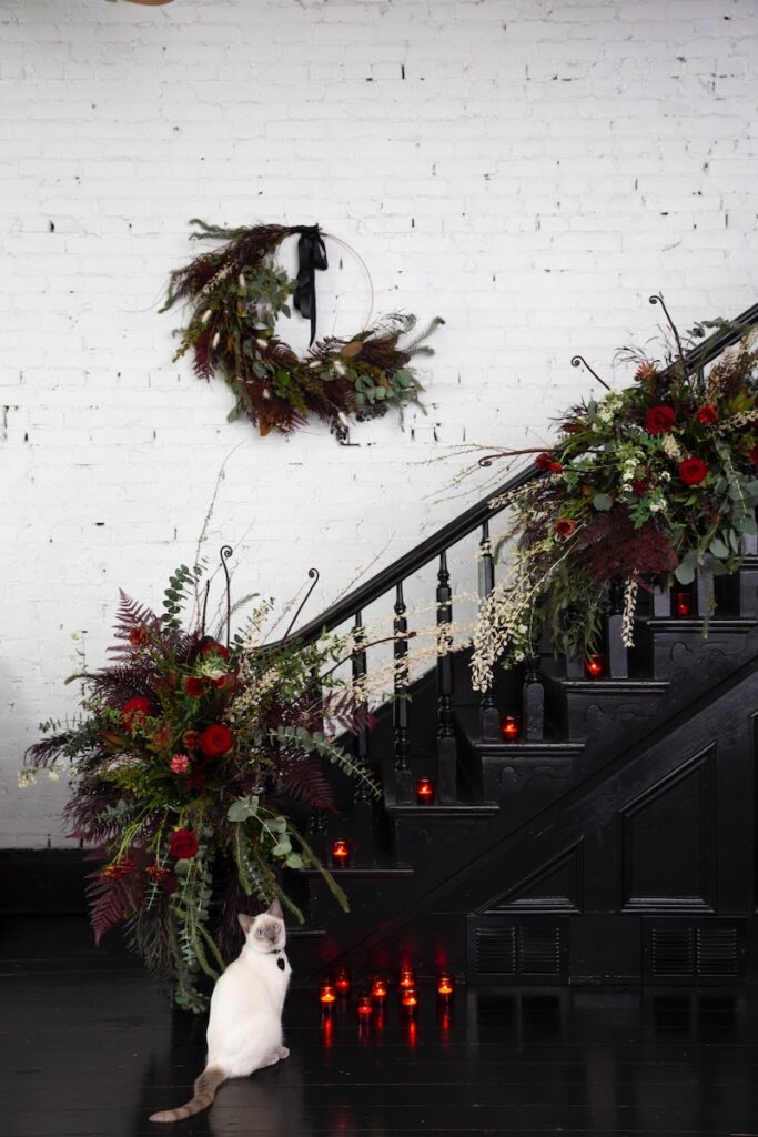 Image of staircase decorated with wreathes and a white cat at the staircase