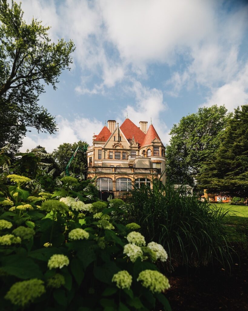 The outside of The Frick Clayton house in the distance, surrounded by trees.