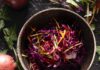 Wintery Red Slaw A bowl filled with vibrant purple and yellow julienned red cabbage, radicchio, and peppers, garnished with scallions.