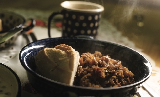 black plate with steaming polish food with black mug