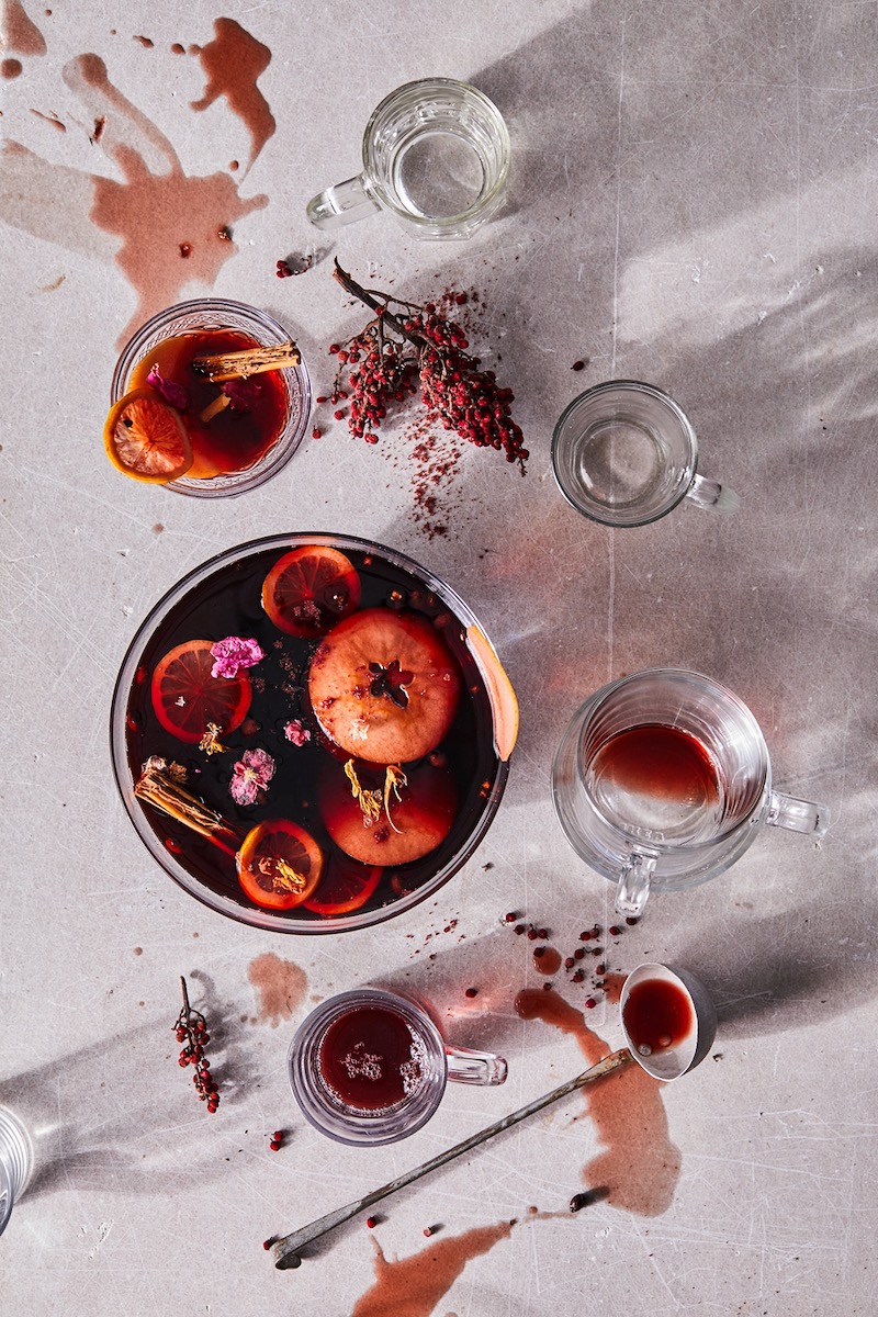 A glass of mulled wine on a white background, garnished with fruit