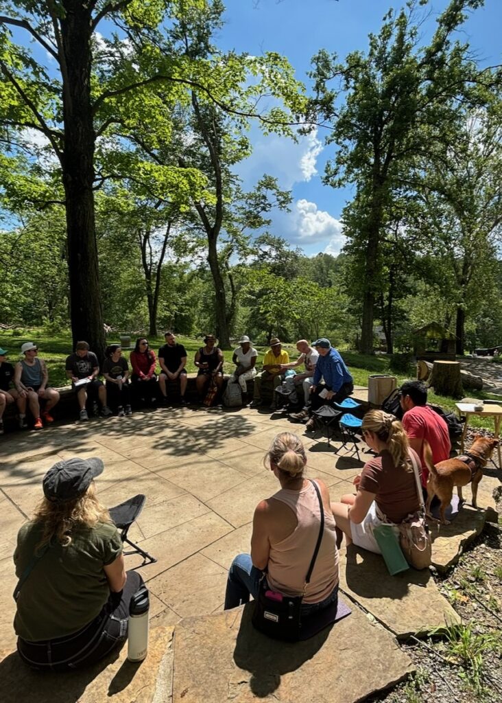 A group of people sit in a circle in Pittsburgh's forests.