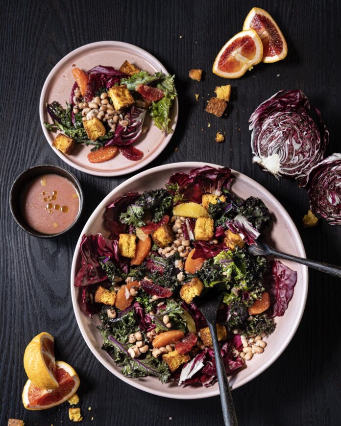 Black Eyed Peas Salad TABLE Magazine 2 A big white bowl of salad with various toppings and black eyed peas beside a small pink plate with the salad on it.