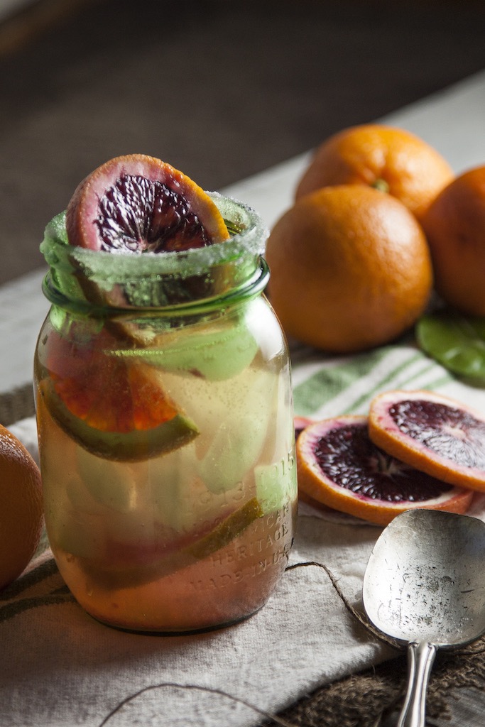 A blood orange sangria in a glass jar with slices of blood orange, mint, and lime. 