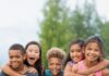 Giving Guide 2025: The Child Health Association of Sewickley Two children give two other kids piggy back rides as another child stands between them.