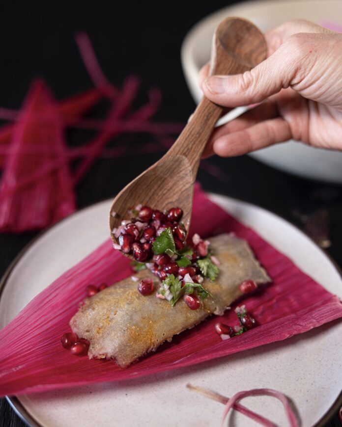 Good Luck Tamales TABLE Magazine 2 A person spoons a filling onto a hot pink tamale.