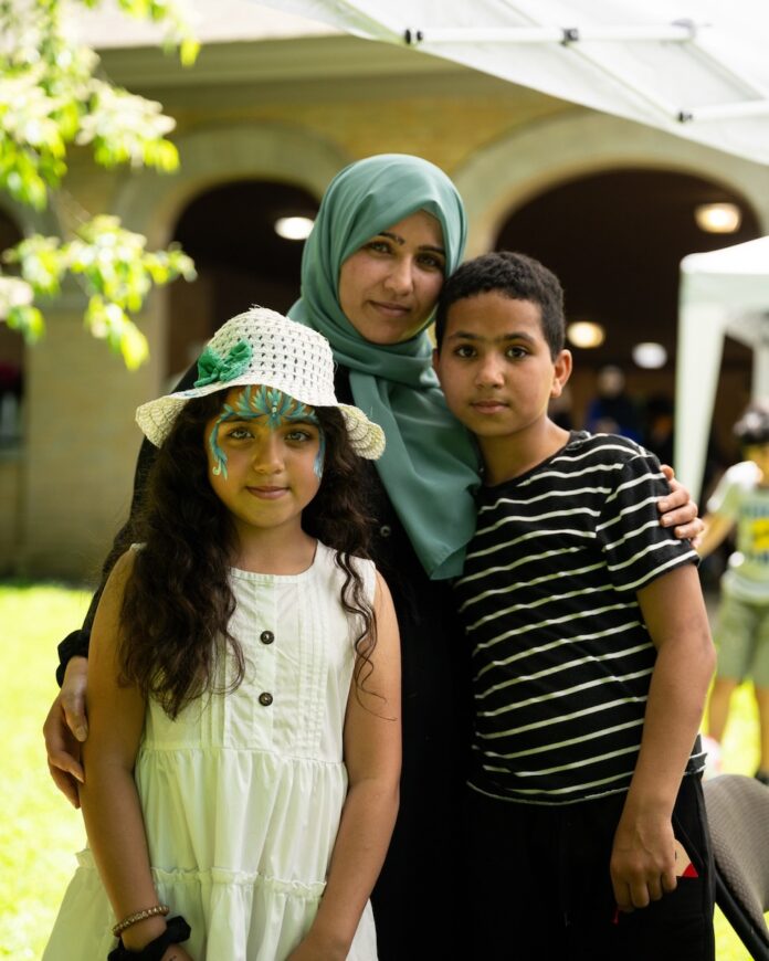 Two children and a mother in a blue hijab.