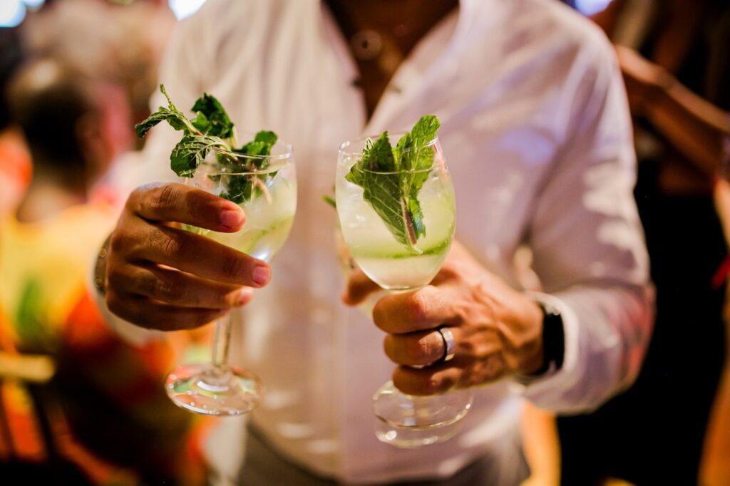 A man holds two cocktails with mint and lime.