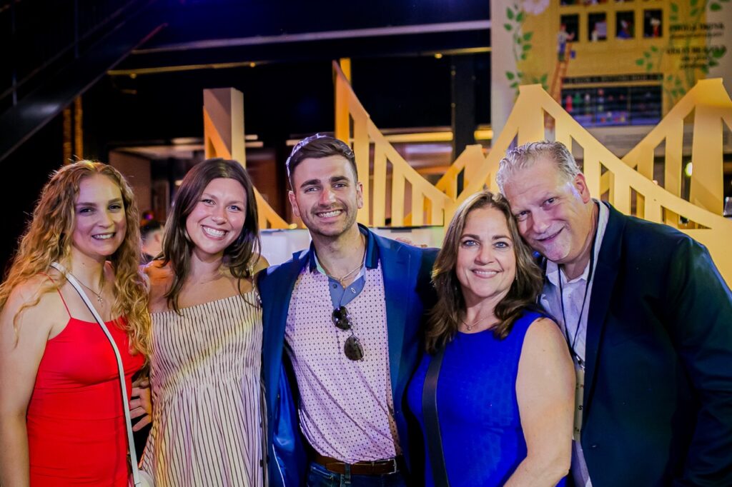 A group of three women and two men stand in front of fake yellow bridges.