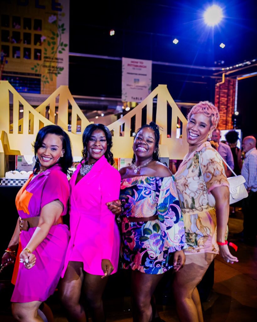 Four women pose together in front of fake yellow bridges.