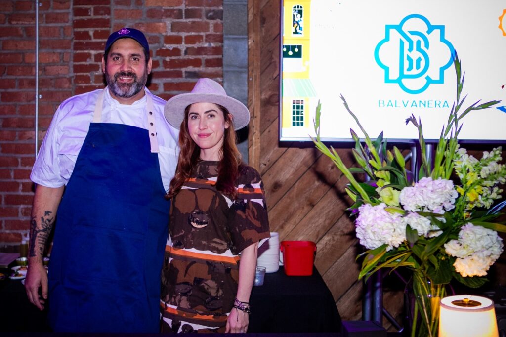 A man in a blue apron and a woman in a brown dress.