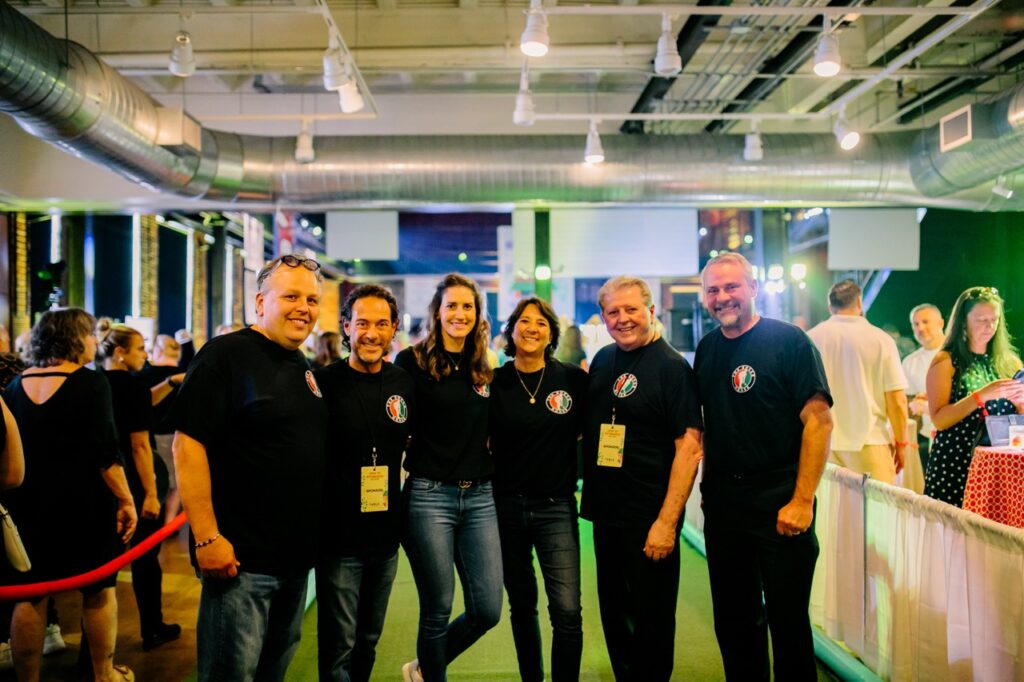 A group of 6 bocci team members in black shirts on a fake green.