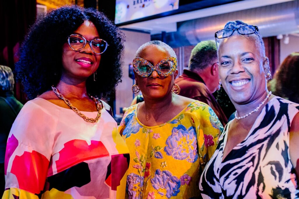 Three women with glasses stand together.