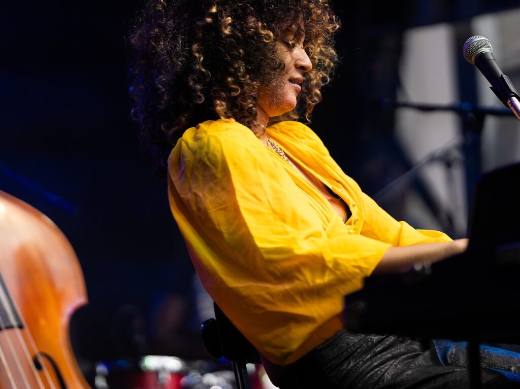 A woman in yellow plays the piano.