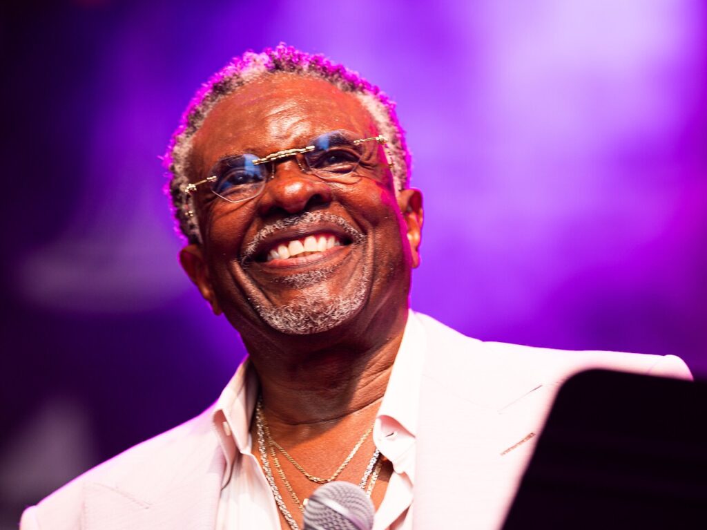A man smiles with a purple light behind him.