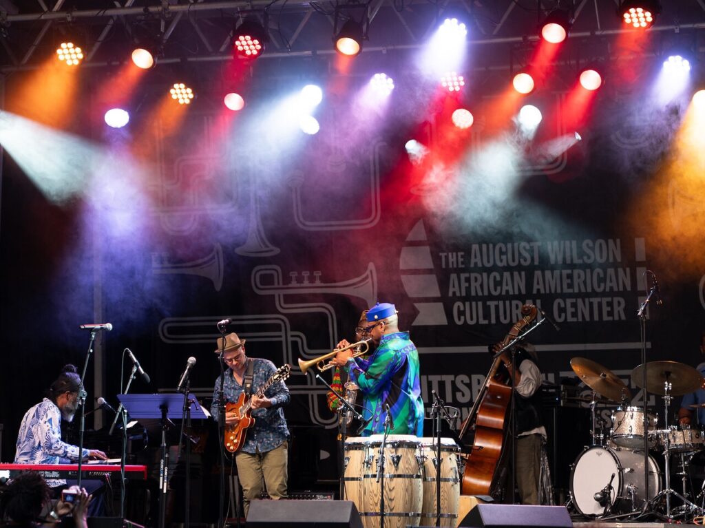 A group of musicians play on the jazz fest stage.