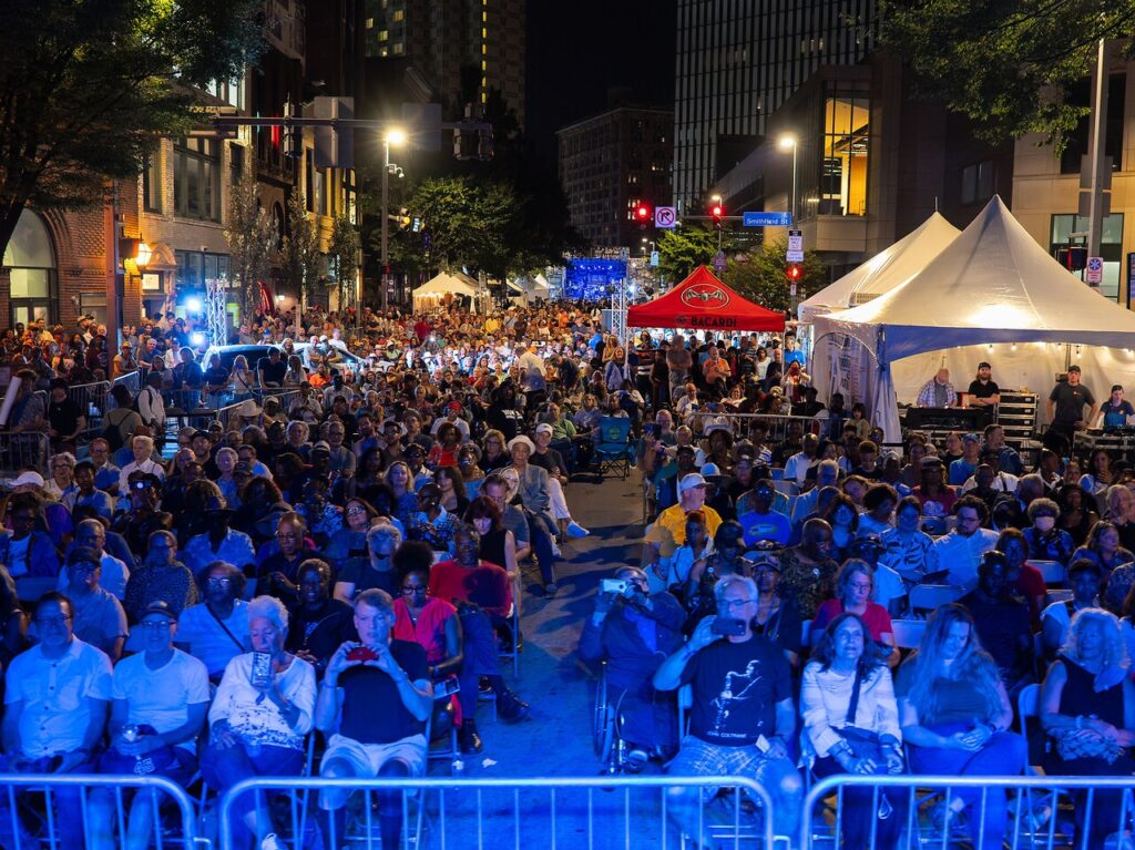 A crowd of people sitting outside in blue lighting.