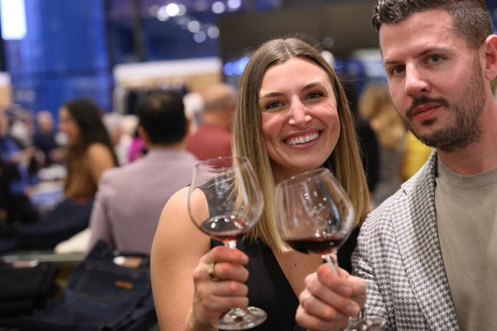 A man and woman cheers wine glasses.