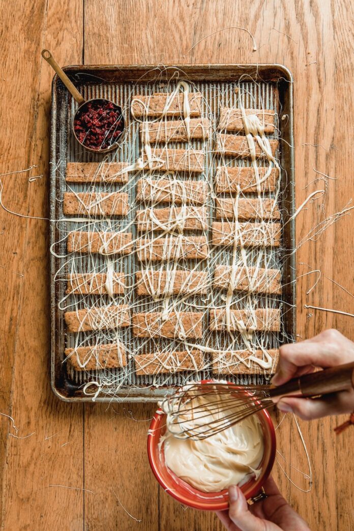 Drizzling Icing over cookies on baking sheet