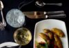 LeMont’s Chicken Christina A plate of LeMont's Chicken Christina with roasted potatoes, asparagus, and a tomato basil coulis, served alongside bread, a glass of white wine, and water on a black tablecloth, emphasizing fine dining cuisine.