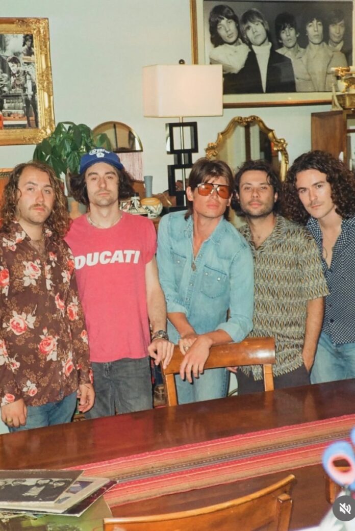 A photo of Mac Saturn the band standing together in a living room area to write music.