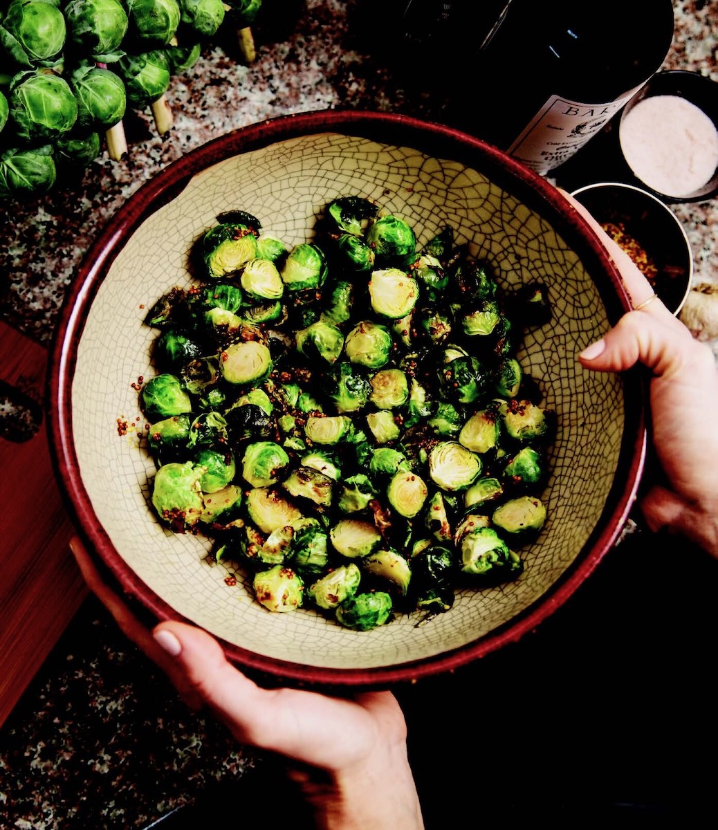 Brussels sprouts in a ceramic dish held in two hands.