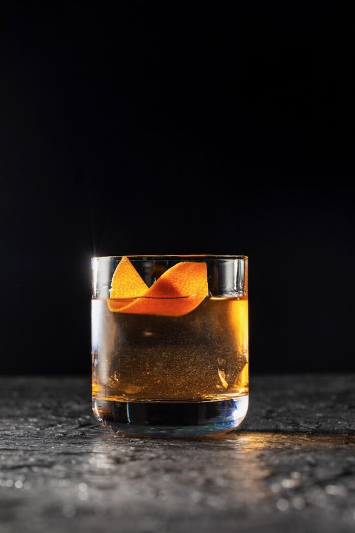 The Vanishing Act, A Now You See Me: Now You Don't Cocktail A short glass with a clear old fashioned for the release of Now You See Me Now You Don't with an orange peel twist as a garnish.