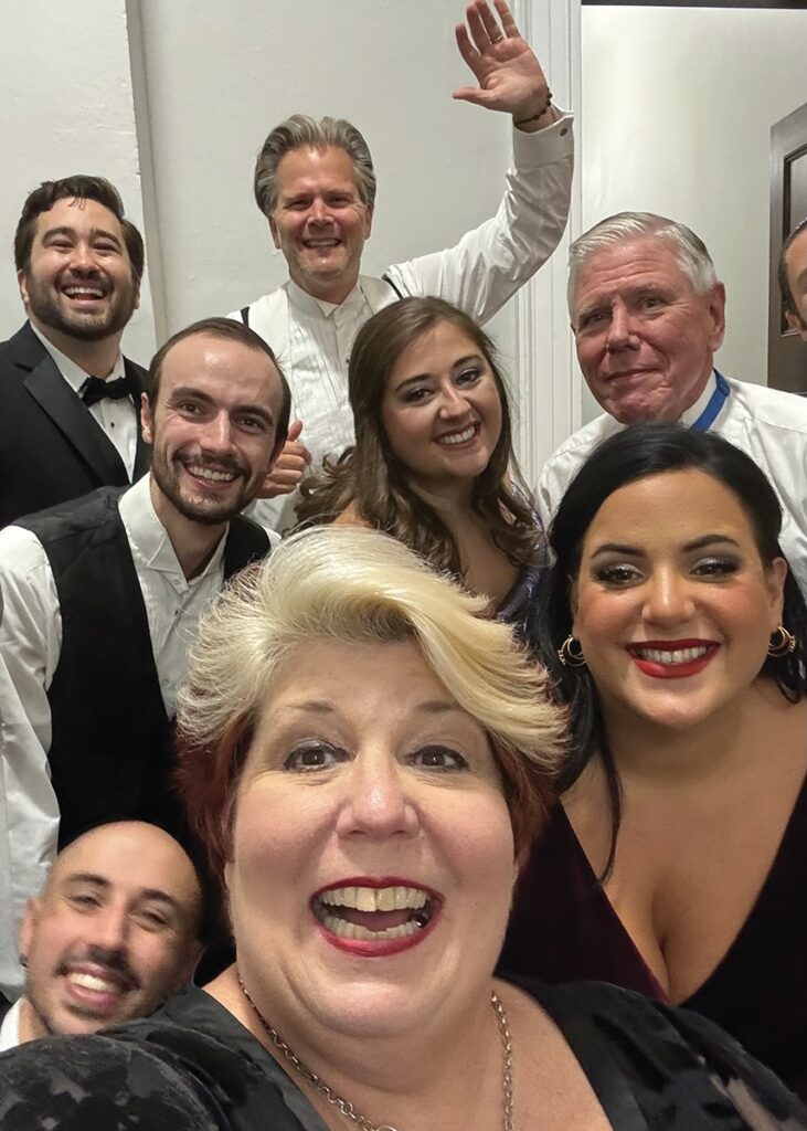 A group of performers smiling in black and white.