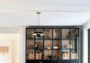 Your Pittsburgh Vintage Store Roundup from Interior Designer Leanne Ford A modern dining room with a long natural wood table, black chairs with woven seats, a black display cabinet with woven baskets, and a hanging black and brass light fixture.