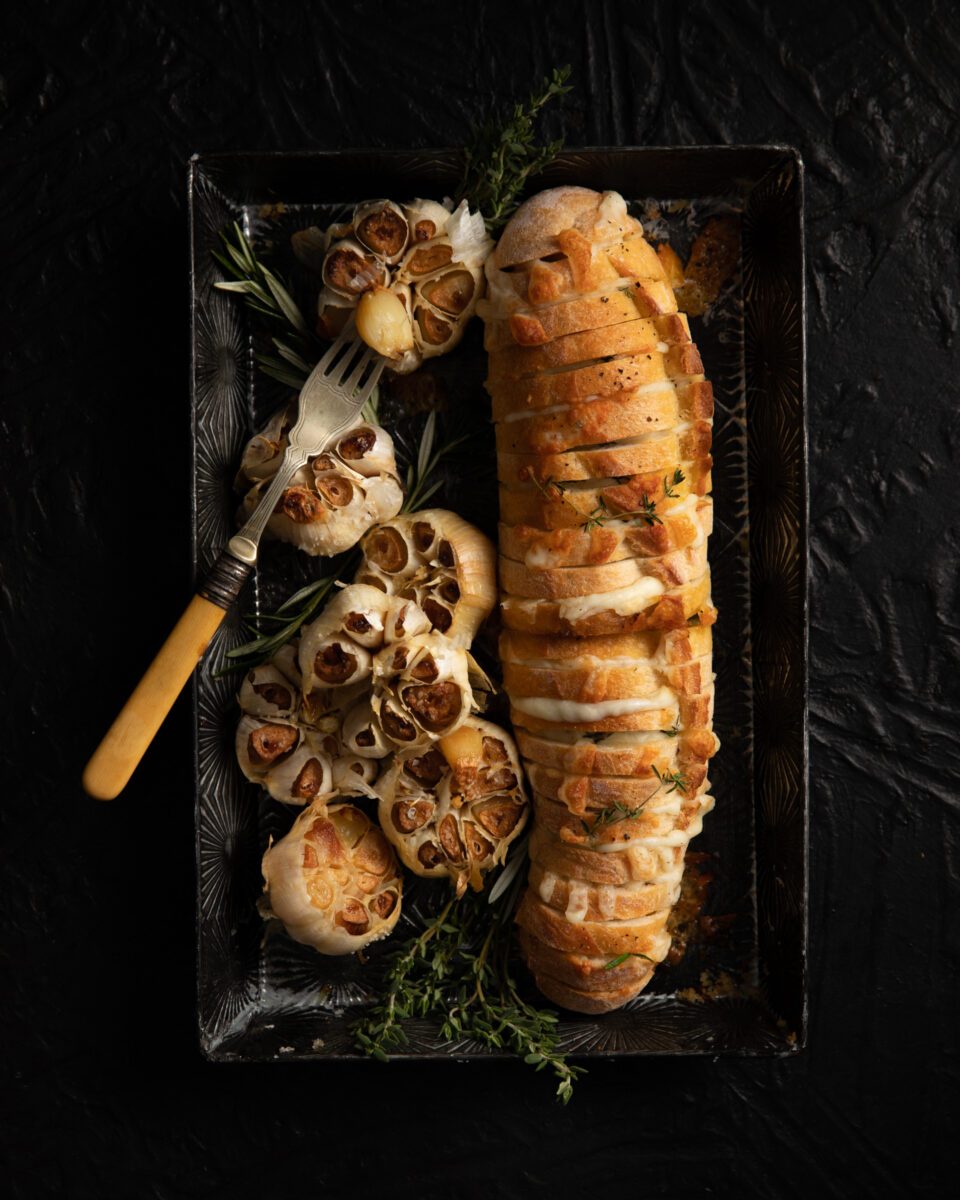 Roasted Garlic with Cheesy Bread served on a black tray with a fork