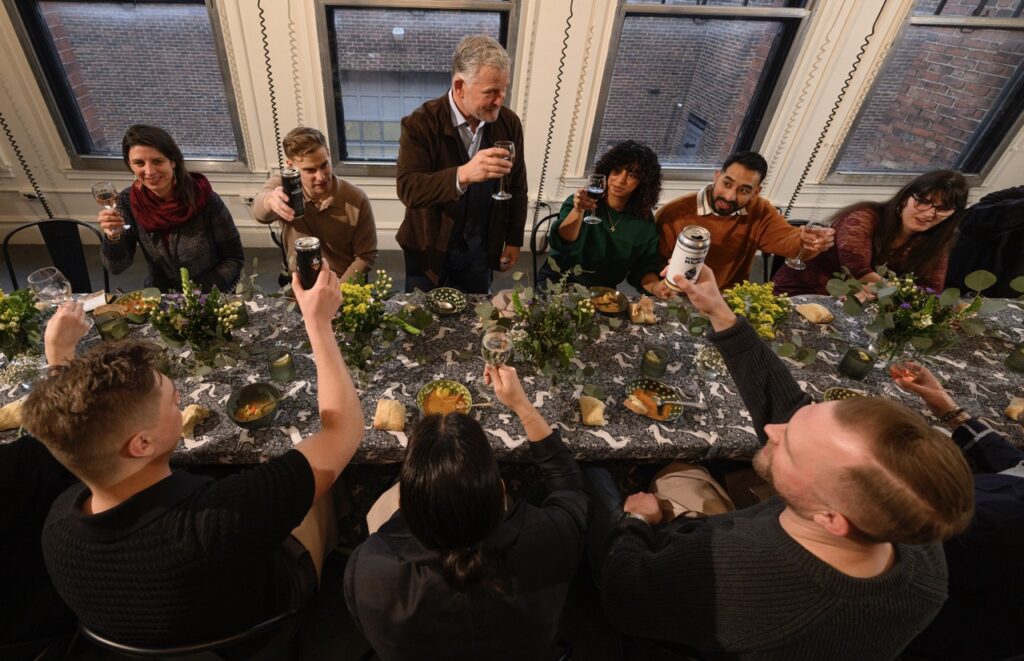 A group of people toast at a long black table.